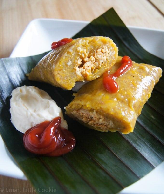 Pasteles en hoja served on a plate with a red and white sauce.