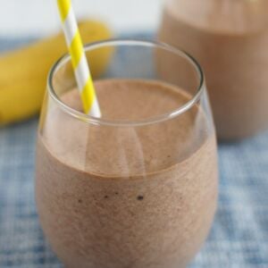 A banana Nutella milkshake poured into a glass with a straw.