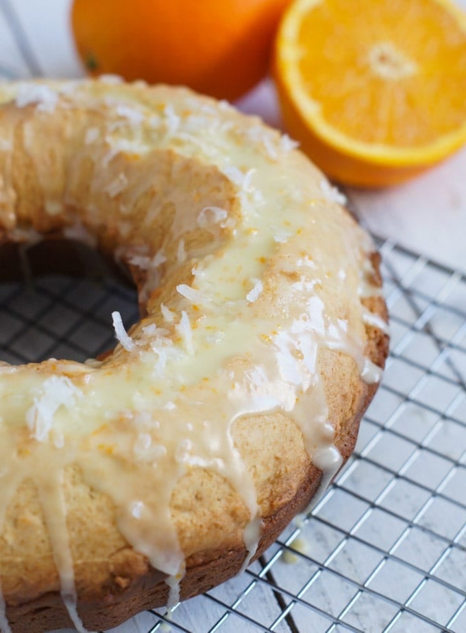 Close up of an orange ricotta coconut cake on a cooling rack.