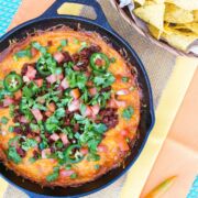 Queso topped with chorizo and fresh herbs in a skillet.