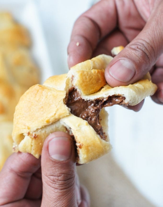 A crescent roll being broken in half to reveal the smores filling.