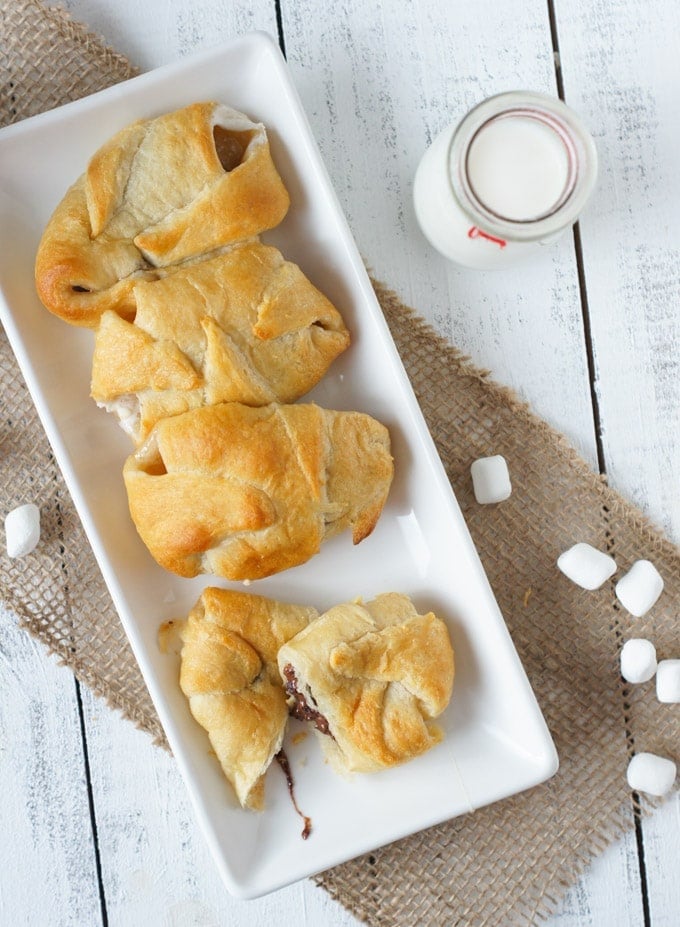 Overhead shot of four smores crescent rolls on a white plate.