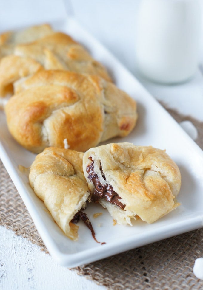 A plate of smores crescent rolls with one broken in half.