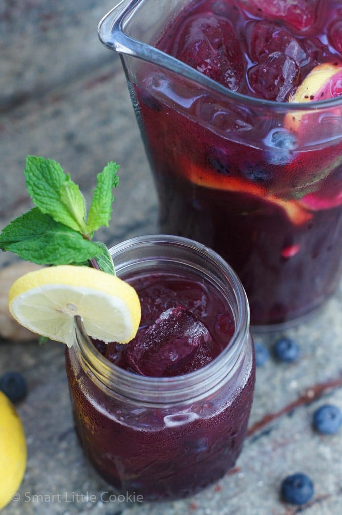 Blueberry lemonade in a pitcher and poured into a mason jar.
