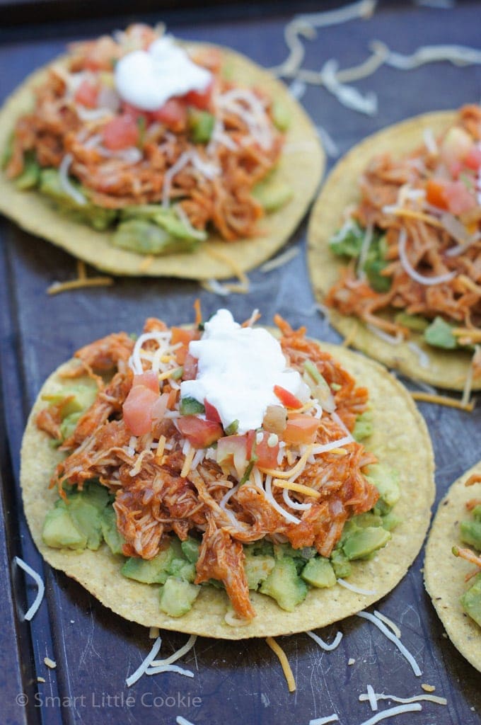 Close up of avocado and chipotle chicken on a tortilla, topped with shredded cheese and sour cream.