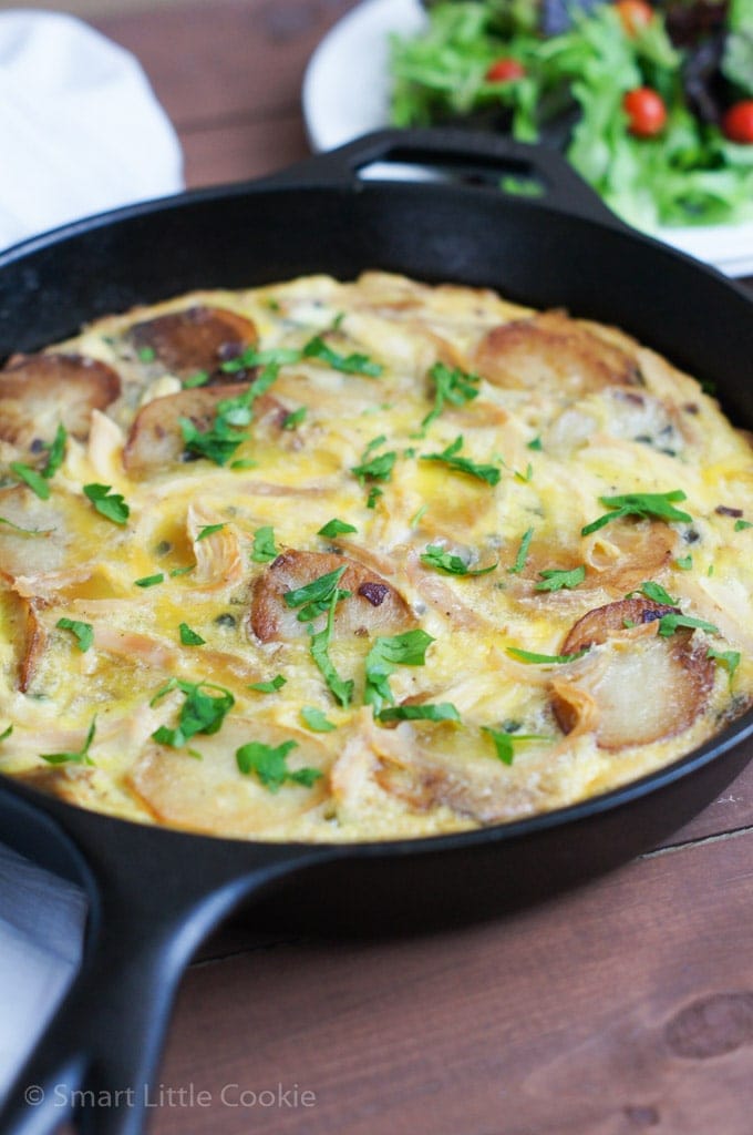 A chicken tortilla in a cast iron pan and garnished with fresh herbs.