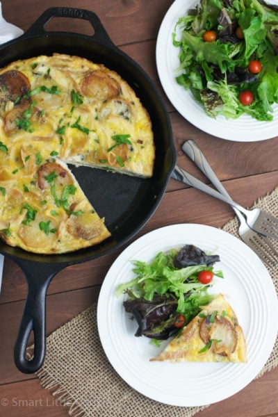 A Spanish tortilla in a skillet with a piece served on a plate with a side salad.
