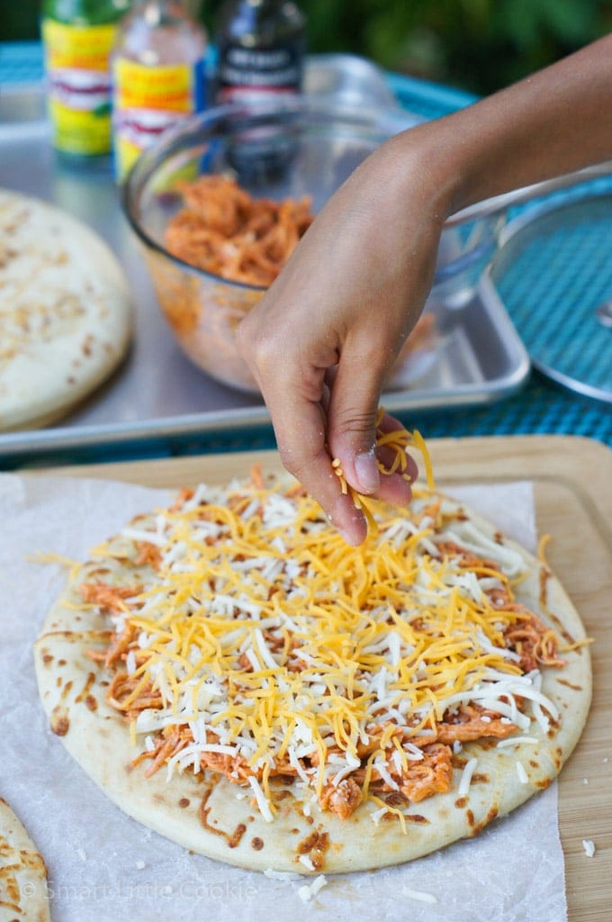 Adding shredded cheese to the pizza.