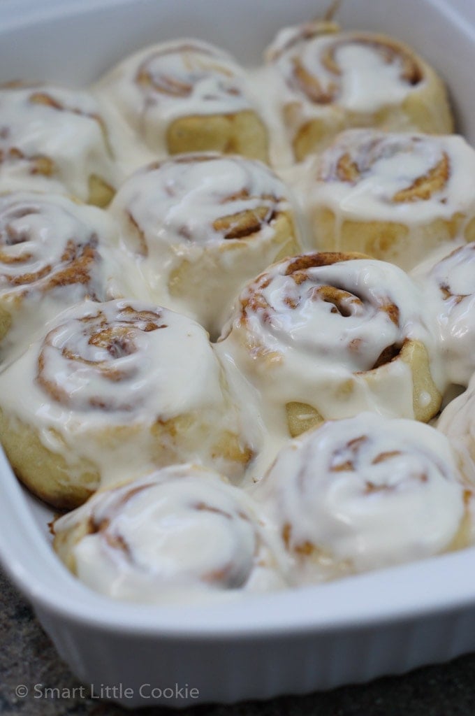 Iced cinnamon rolls in a baking dish.