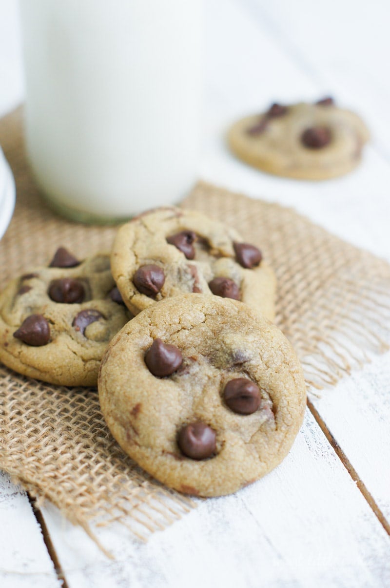 Three chocolate chip cookies on a table mat.