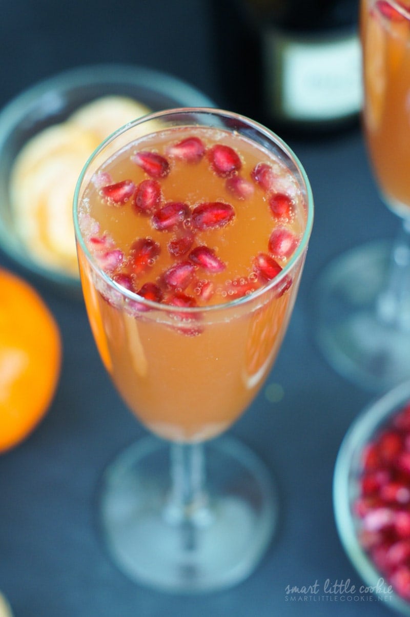 A mimosa served in a flute glass and topped with pomegranate seeds.