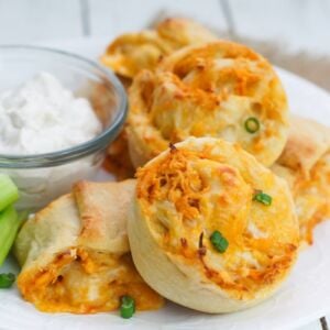 Buffalo chicken rolls garnished with chives and served with a dip.
