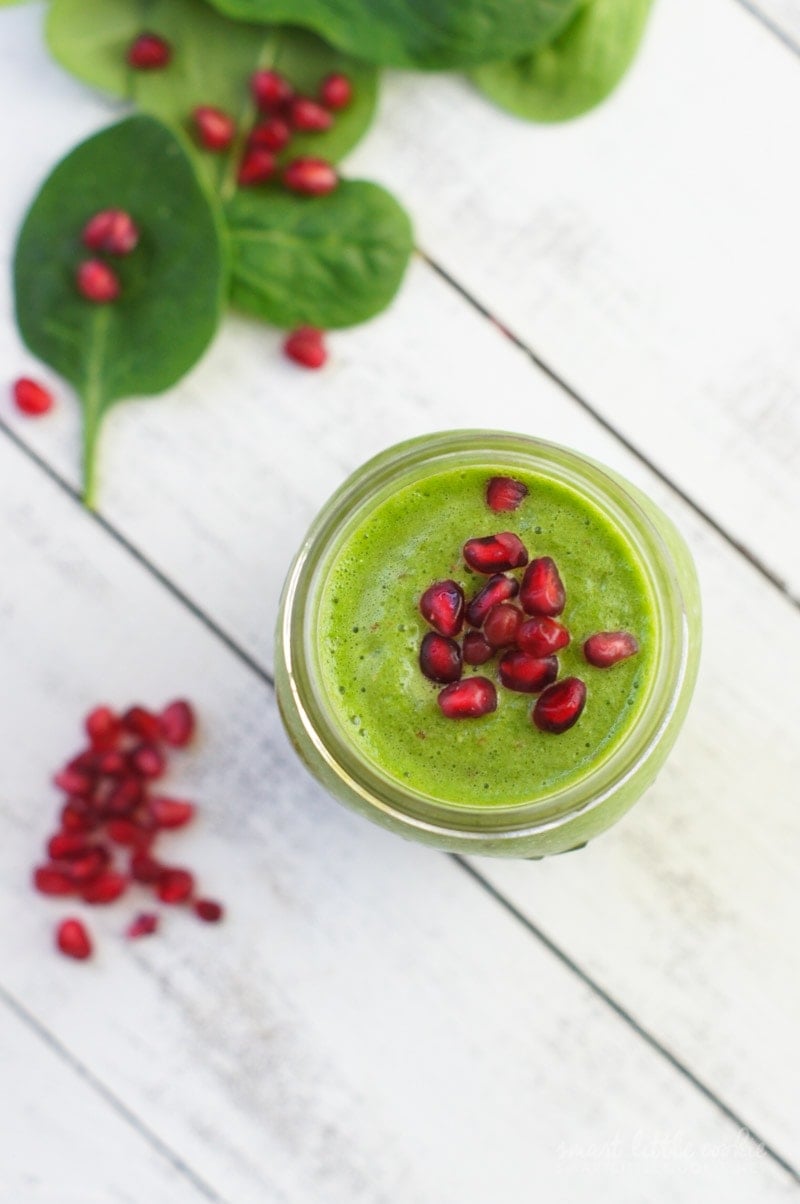 Overhead shot of a green smoothie topped with pomegranate seeds.