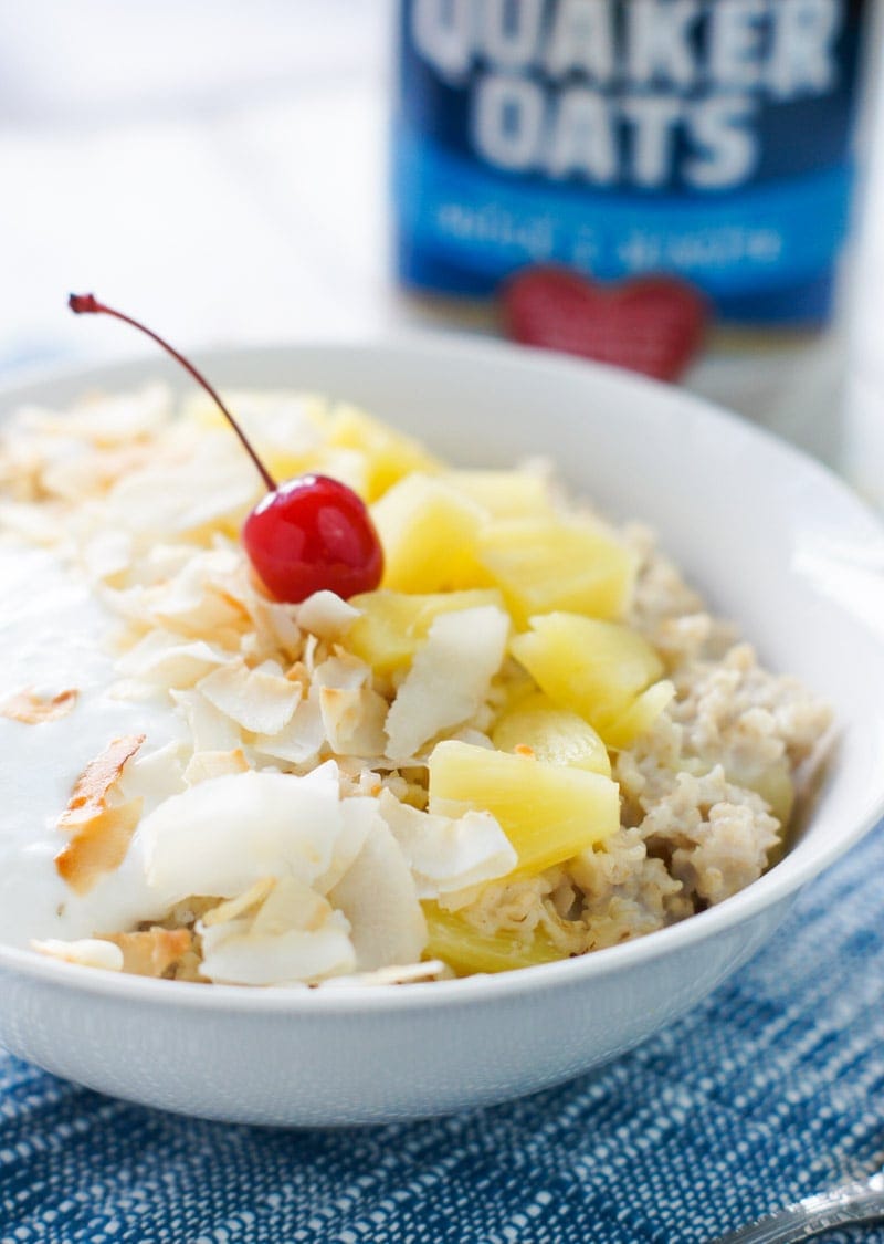 Oatmeal topped with fresh pineapple and a cherry.