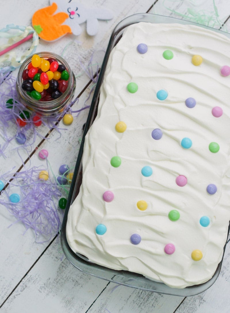 Chocolate tres leches cake in a baking dish topped with frosting and m&ms.