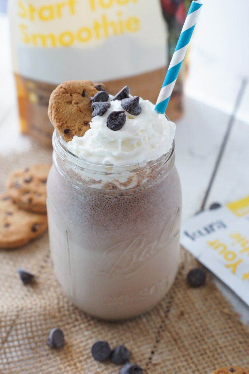 A smoothie topped with whipped cream, chocolate chips and a cookie.