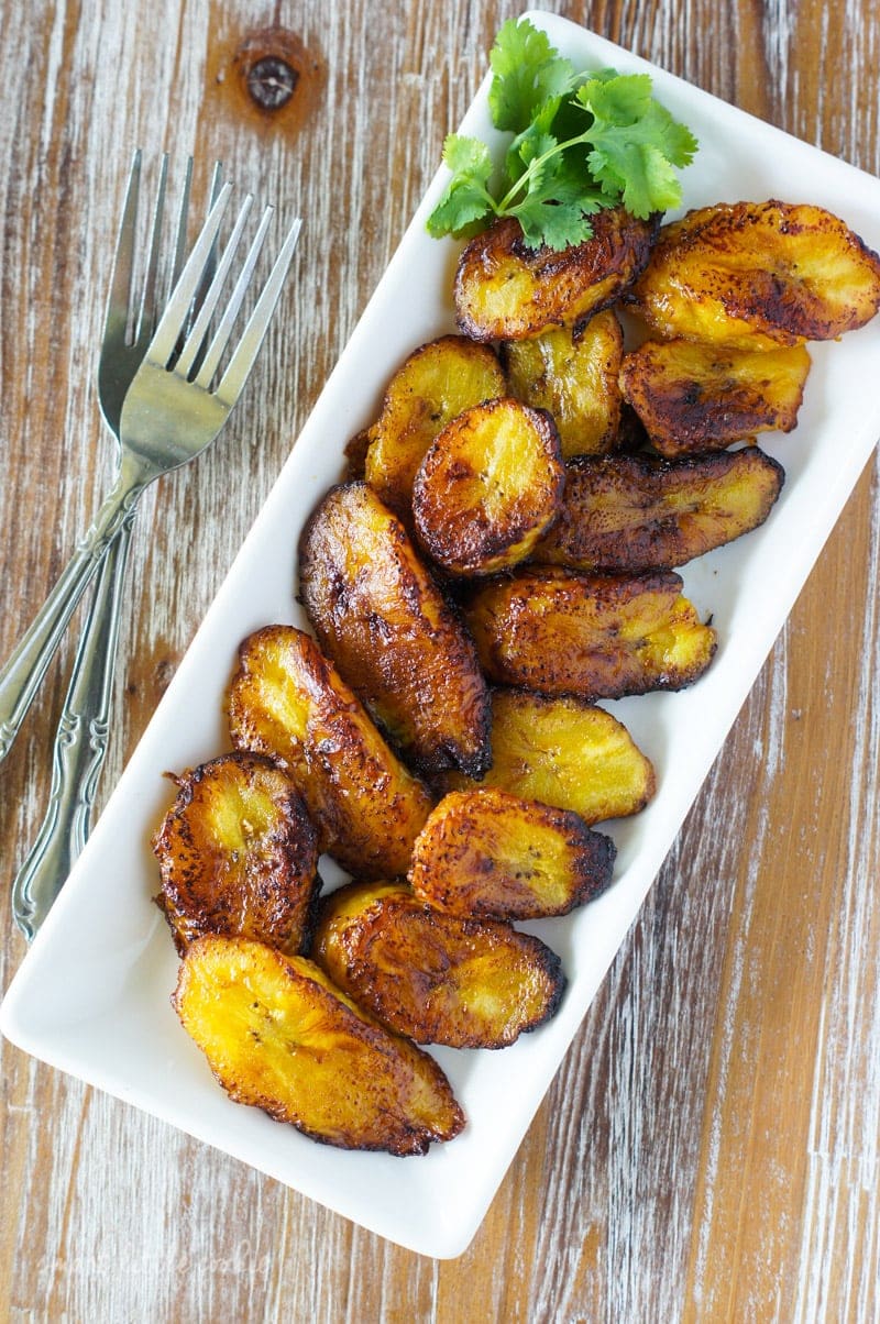 Golden Fried Sweet Plantain Slices (Platanos Maduros Fritos) served on a long white plate.