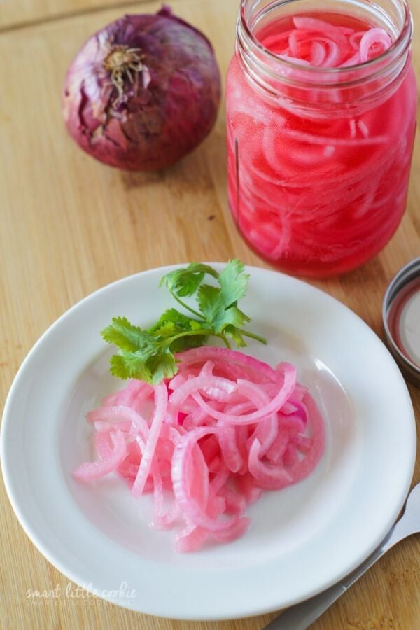 Pink pickled onions on a white plate.