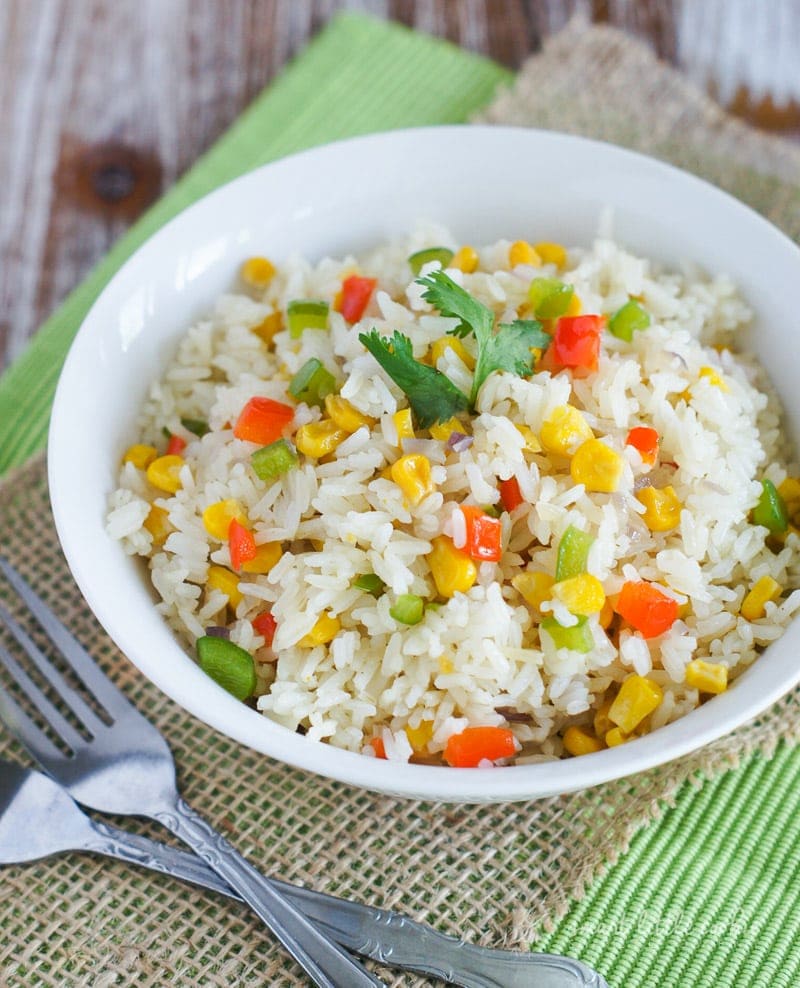 Arroz primavera served in a white bowl next to two forks.