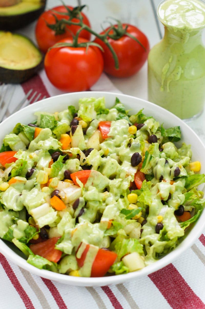 Aderezo de aguacate y cilantro rociado encima de una ensalada en un plato