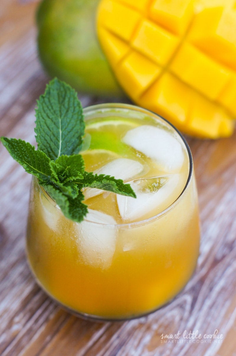 A mango mojito served in a glass with ice and a sprig of mint.