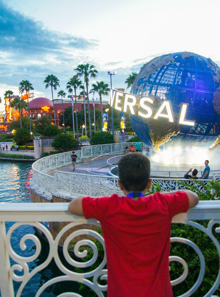 A boy leaning over railings looking at the Universal globe.