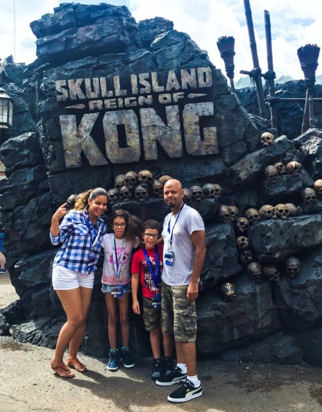A family in front of a sign for the Skull Island attraction.