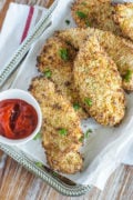 Baked chicken tenders served on a white plate with a red dip.