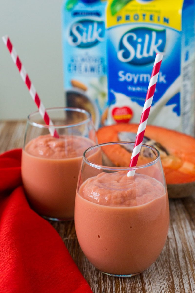 Two smoothies in front of a carton of soy milk.