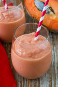 A pink smoothie in a glass with a straw.
