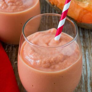 A pink smoothie in a glass with a straw.