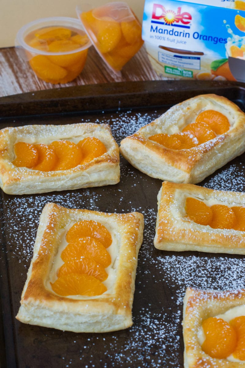 Five mandarin pastelitos dusted with powdered sugar. 