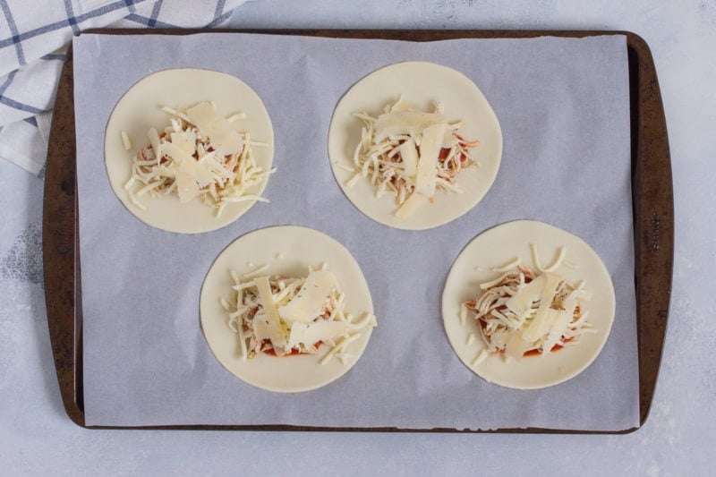 Four discs of empanada dough topped with the filling before being folded.