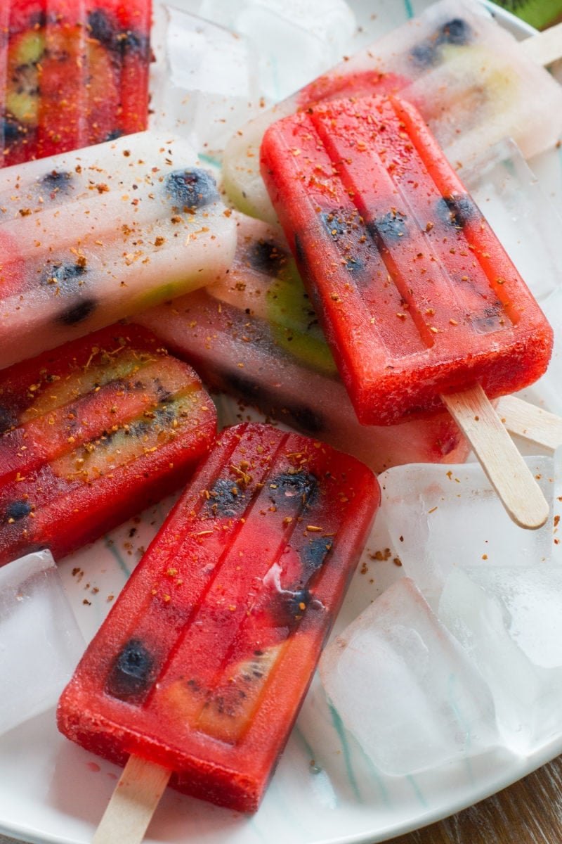 Six fruit popsicles stacked on top of each other and sprinkled with tajin.