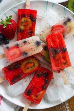 Overhead shot of different colored fruit popsicles sprinkled with spices.