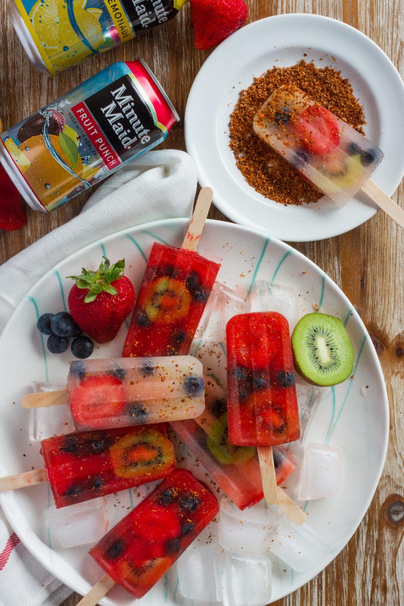 Six popsicles on a plate and one being dipped in tajin.