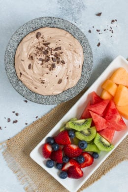 A tray of fruit next to a chocolate dip.