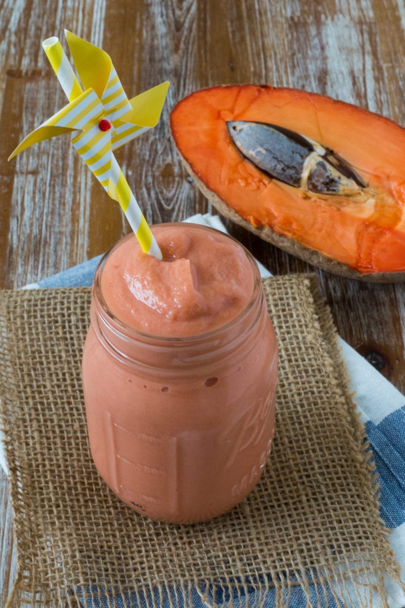 A pink smoothie in a jar with a striped straw.