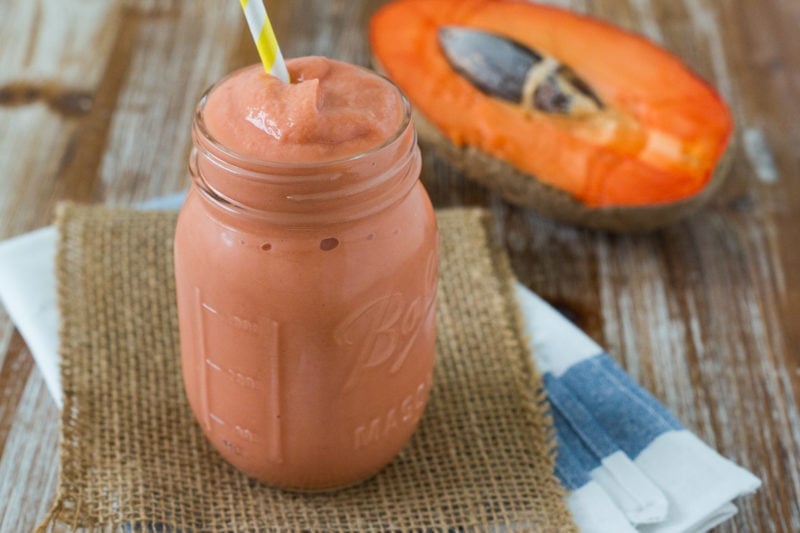 A mamey smoothie in front of a fresh mamey.