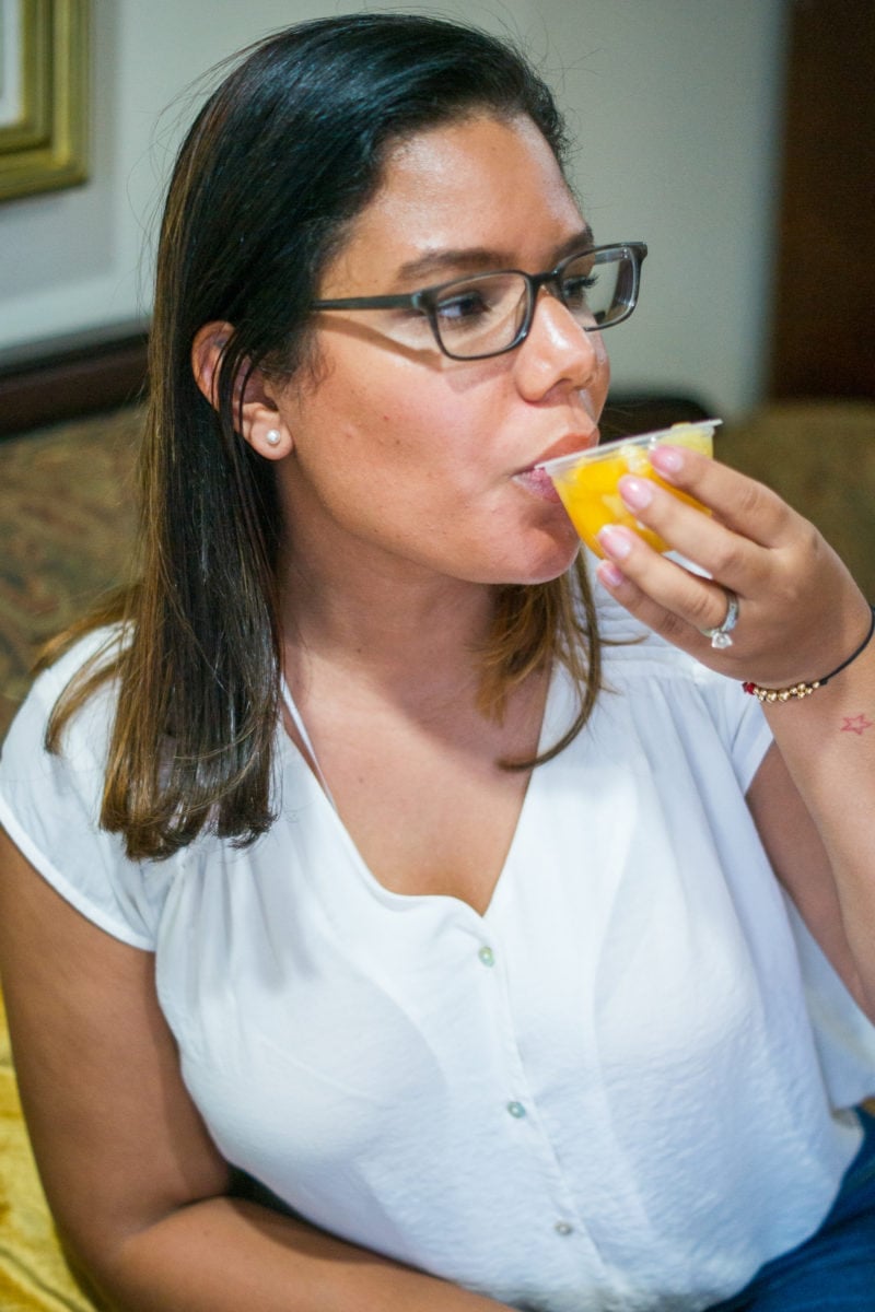 A woman drinking the coconut water from a fruit cup.