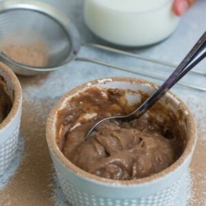 A spoon in a ramekin of chocolate pudding.