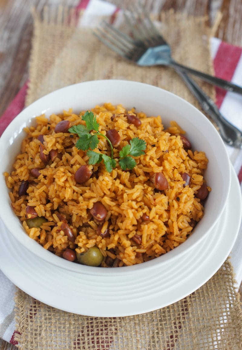 Arroz con frijoles servido en un tazón blanco y cubierto con hojas de cilantro. 