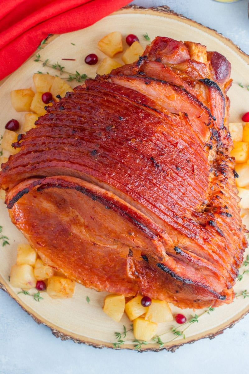 Close up of a glazed sliced ham on a large serving plate.