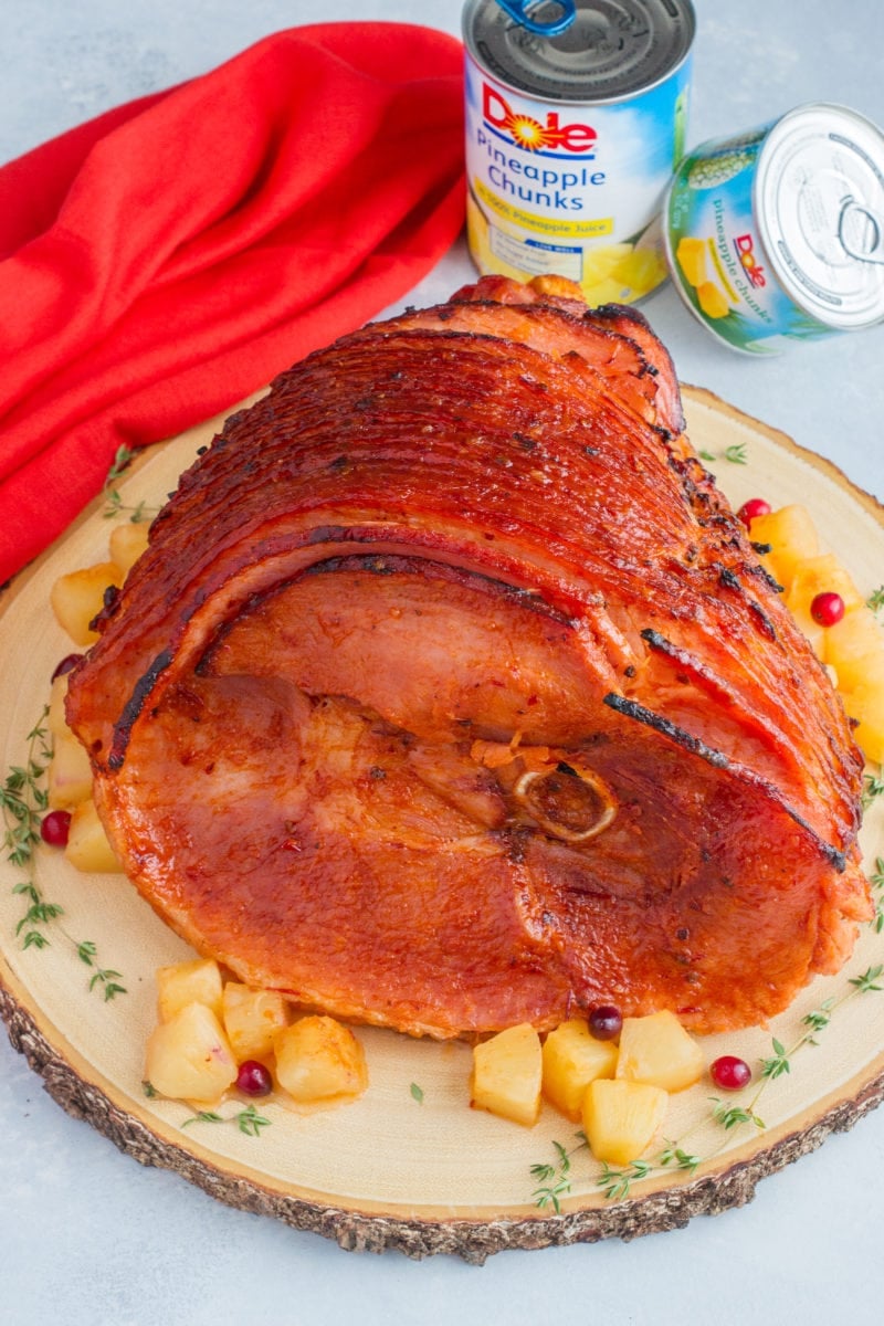 A joint of sliced glazed ham on a large serving plate.