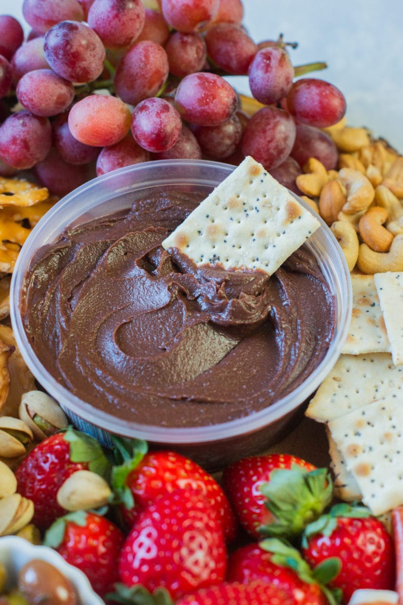 A cracker in a bowl of chocolate hummus.