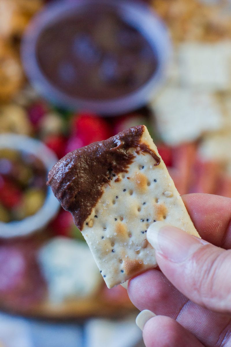 A cracker dipped with chocolate hummus.