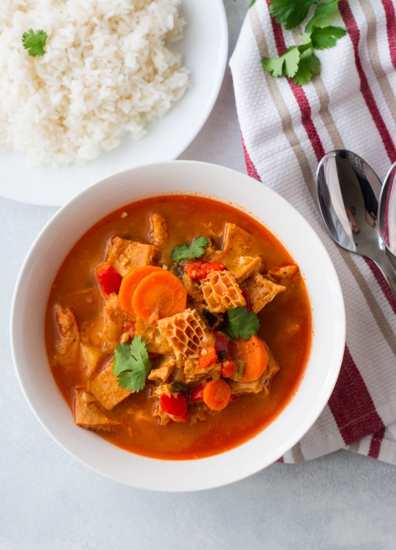 Dominican Style Tripe Stew (Mondongo) served on a white bowl with a side of white rice.