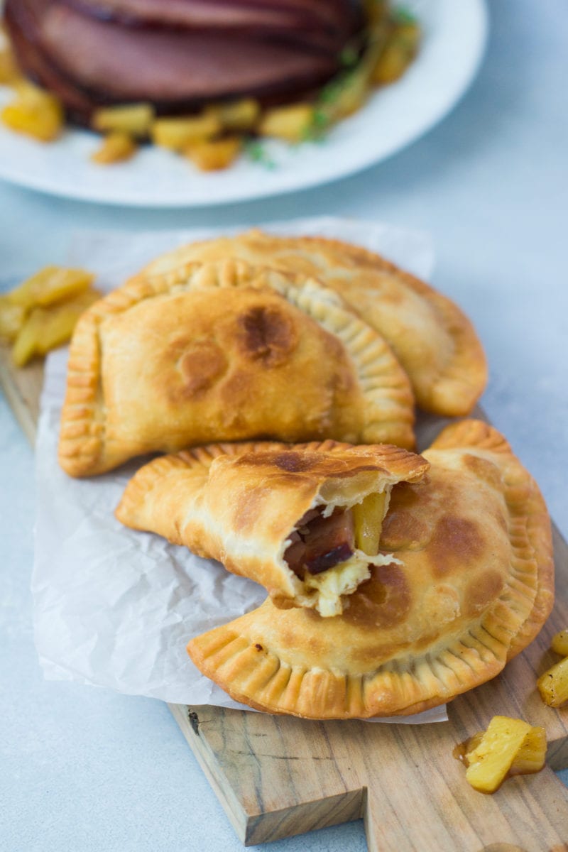 Four empanadas on a board placed on top of each other.