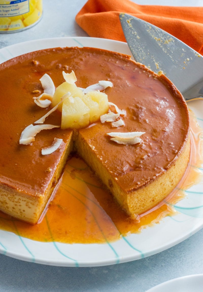 The flan on a plate with a slice taken out of it.