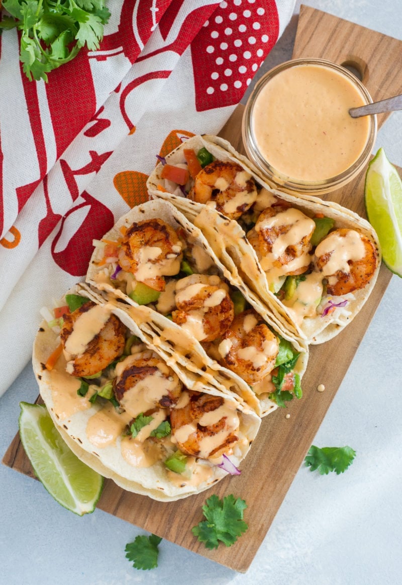 Easy Shrimp Tacos served on a wooden board and drizzled with Pineapple Chipotle Sauce 